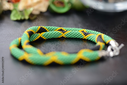 Necklace in colors of Jamaican flag on a dark background close up