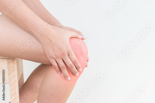 Young woman with hands holding knee pain isolated on white background.