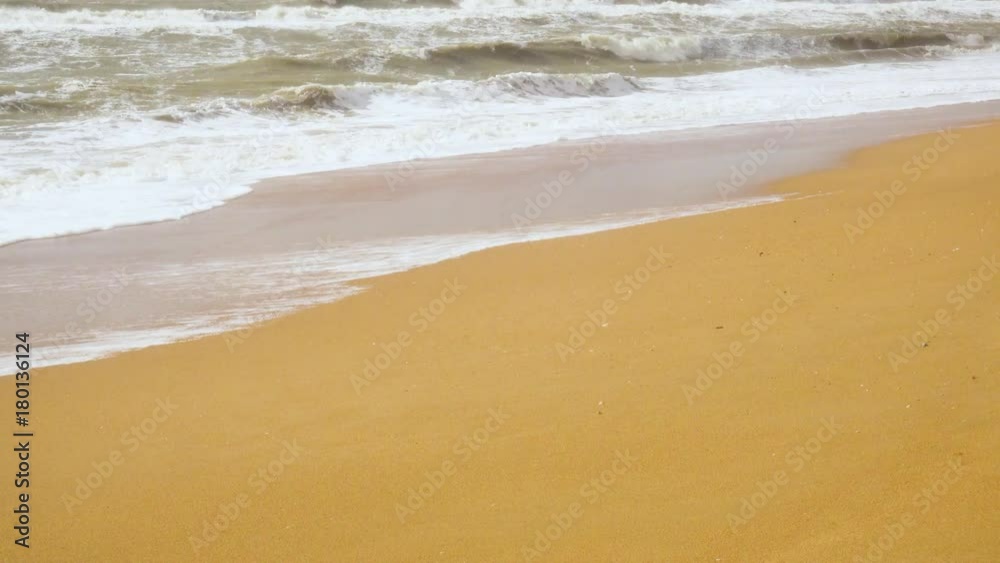 Turbid foam waves rolling on a yellow sandy beach under the sunlight Turbid foam waves rolling on a yellow sandy beach under the sunlight