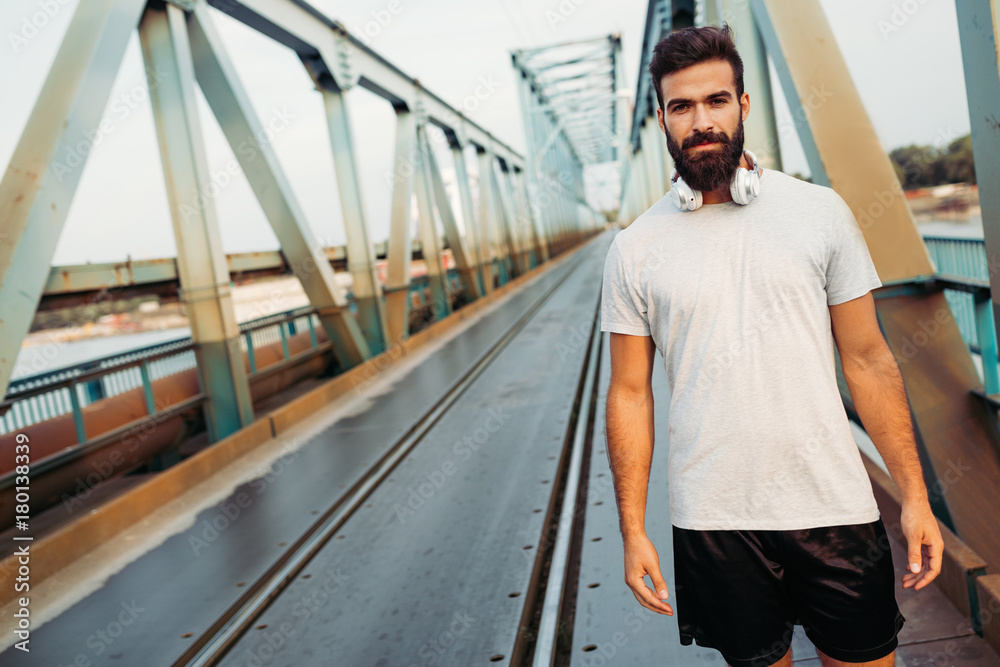 Obraz premium Handsome young bearded man running across bridge