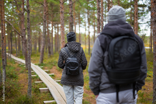 back view of couple with backpacks walking in forest