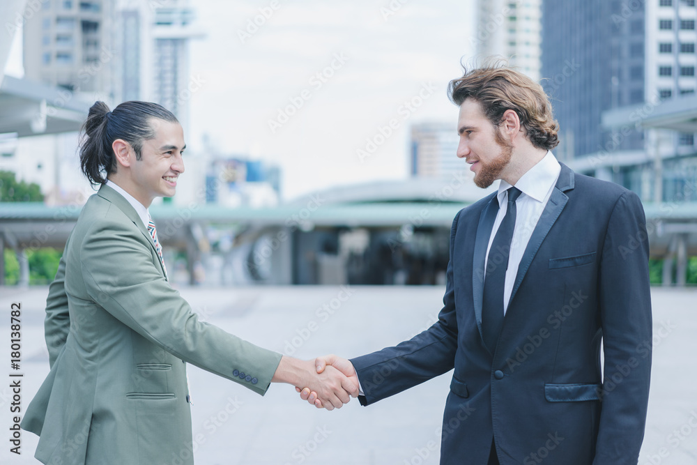 Profession two businessmen shaking hand and smiling after discuss new project success in cityscape background Profession two businessmen shaking hand and smiling after discuss new project success in cityscape background