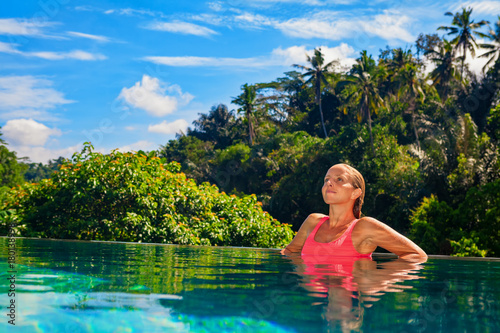 Beautiful tanned woman on summer beach holiday relaxing in luxury spa hotel in infinity swimming pool with tropical jungle view. Healthy lifestyle, family travel background. Bali island tour. © Tropical studio