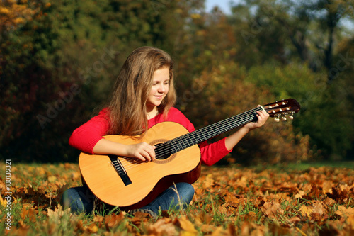 Beautiful girl with a guitar in the park