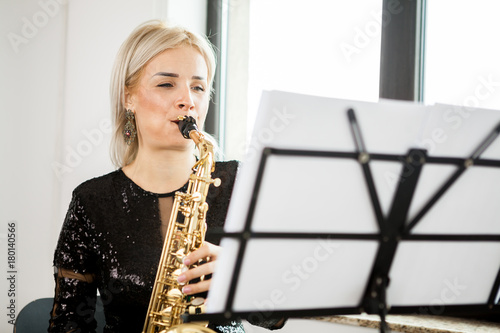 Canvas Print Gorgeous Saxophonist woman with her musical instrument at the window