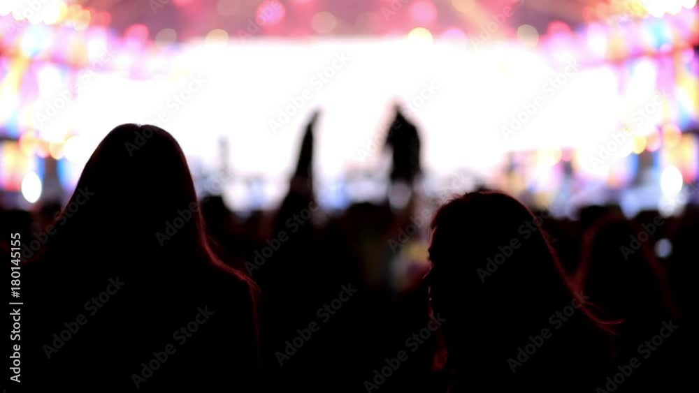 Dancing girl fan silhouettes on concert flashing light cheerful hands in air