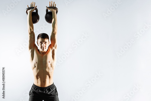 Young strong man exercise with dumbbells on gray background