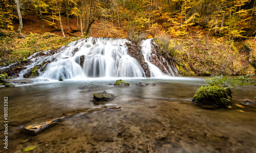 Autumn waterfall in a wood. Picturesque wood in warm colors.