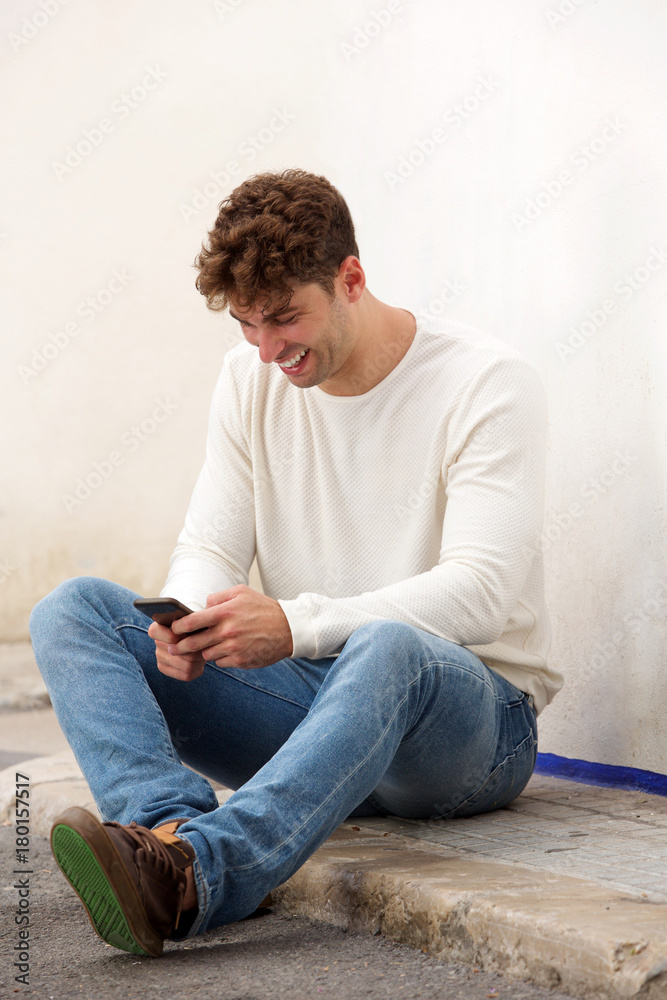 laughing man sitting on ground with mobile phone laughing man sitting on ground with mobile phone