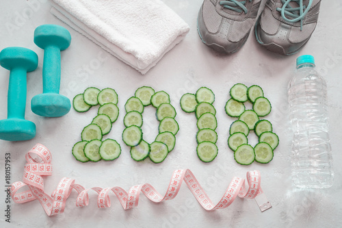 Sneakers, towel, water and dumbbells. Cucumber sliced symbol of the new year.