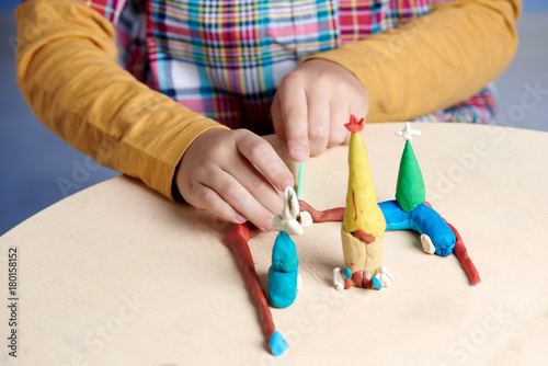 Boy is sculpting with colorful modelling clay. Close up.