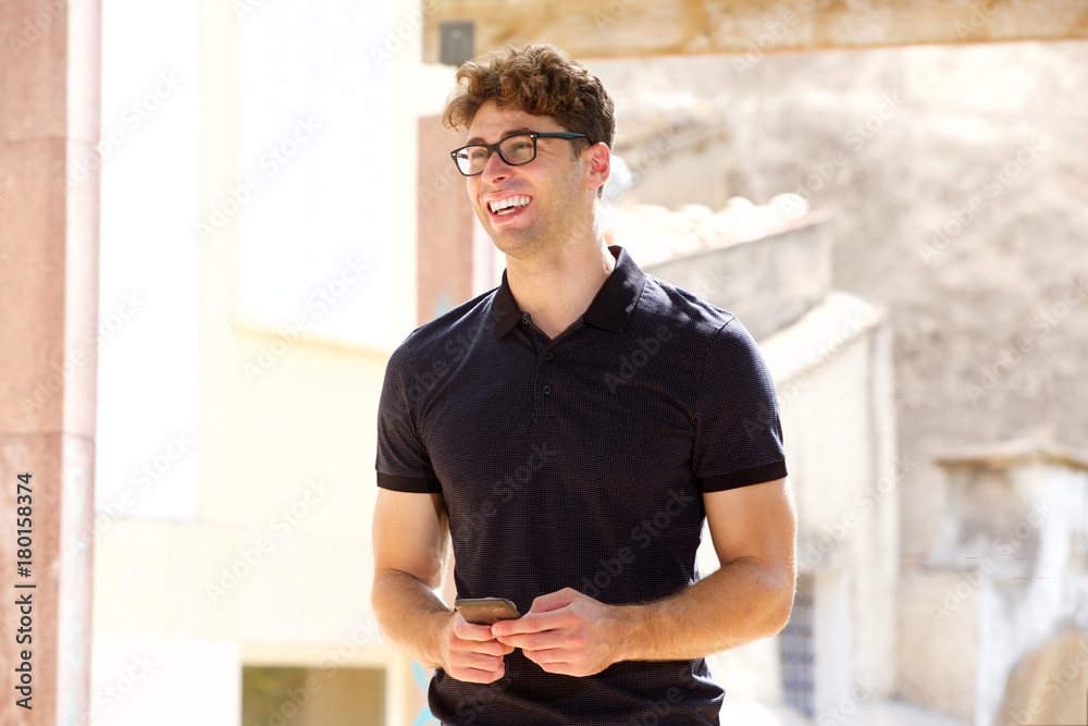 Obraz premium Handsome man smiling and holding mobile phone