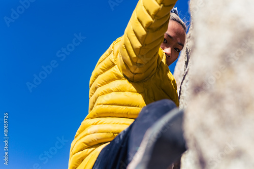 Принти на полотні Petite asian woman rock climbing outdoors hangs from stone wall while wearing a