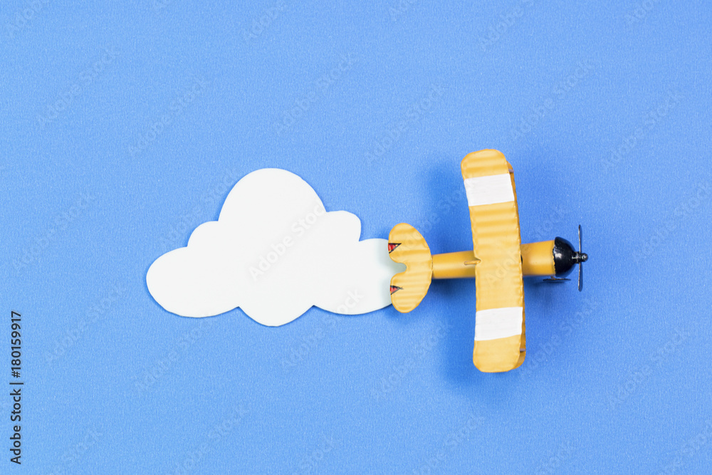 toy airplane on a background of blue sky with paper clouds. The concept