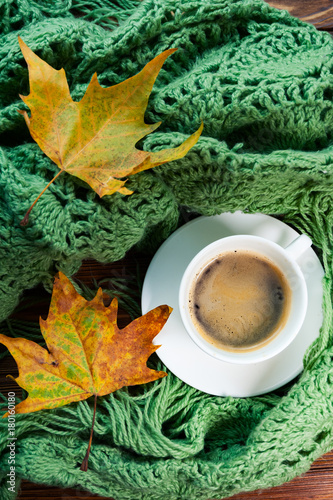 Top and vertical view  of cup of hot coffee and warm green scarf. Concept of coziness and warmth photo