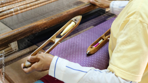 Fotografie Weaver is putting shuttle into weaving machine to make silk