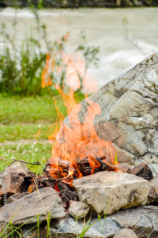 Camp fire. Bonfire diluted in the rocks against the background of the forest