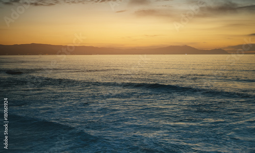 Clouds blue sky and gold sunlight sunset on horizon ocean  background seascape dramatic atmosphere rays sunrise. Relax view waves sea with ship  mockup nature evening concept  copy space for text.