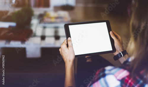 Hipster girl using tablet technology in home atmosphere, girl person holding computer with blank screen on background bokeh, female hands texting on relax holiday, mockup templates 