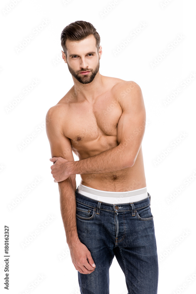 Shirtless and sensual. Handsome shirtless young man in jeans looking at camera while standing against white background. Shirtless and sensual. Handsome shirtless young man in jeans looking at camera while standing against white background.