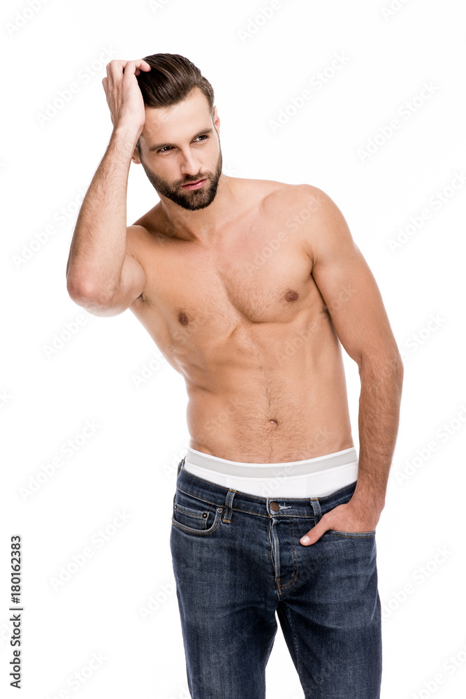 Confident and handsome. Handsome shirtless young man in jeans looking away while standing against white background Confident and handsome. Handsome shirtless young man in jeans looking away while standing against white background