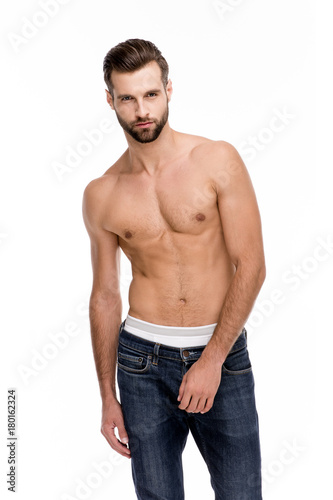 Shirtless and handsome. Handsome shirtless young man in jeans looking at camera while standing against white background.