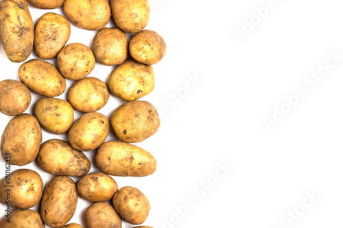 A lot of dirty potatoes on a white background. Potatoes scattered on the left side.