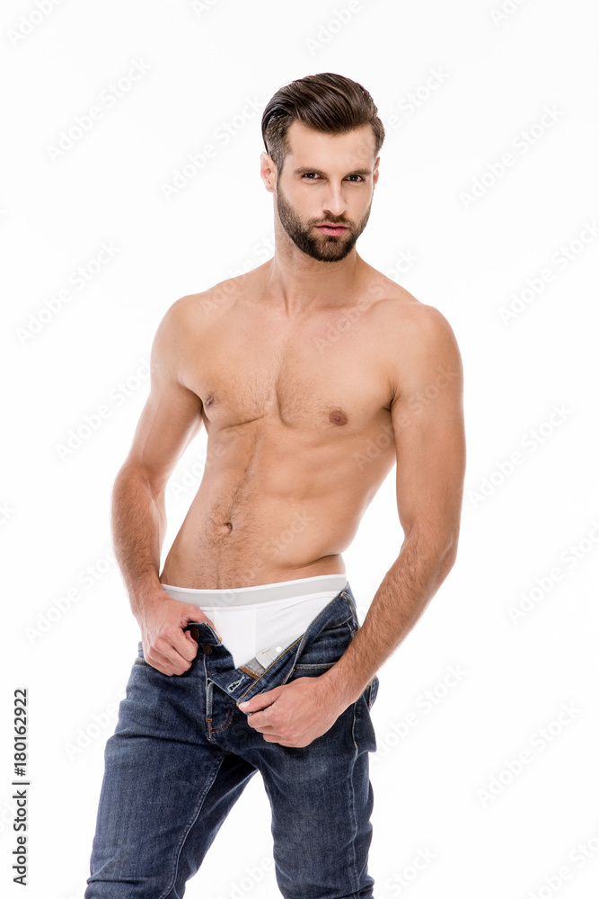 Casual handsome man. Full length of handsome shirtless young man taking off his jeans while standing against white background. Casual handsome man. Full length of handsome shirtless young man taking off his jeans while standing against white background.