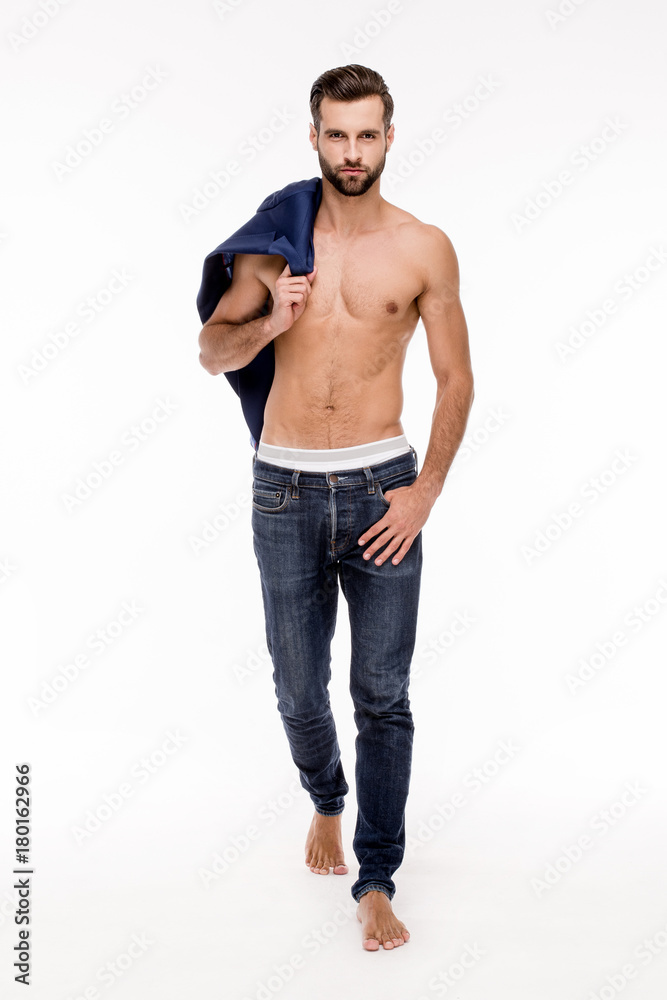 Stylish handsome. Full length of handsome young man in jeans looking at camera and holding his jacket while standing against white background. Stylish handsome. Full length of handsome young man in jeans looking at camera and holding his jacket while standing against white background.