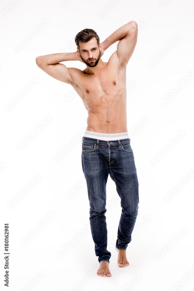 Perfect stubble man. Full length of handsome young man in jeans looking at camera and keeping hands behind head while standing against white background. Perfect stubble man. Full length of handsome young man in jeans looking at camera and keeping hands behind head while standing against white background.