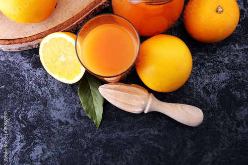 glass jar of fresh orange juice with fresh fruits on dark table