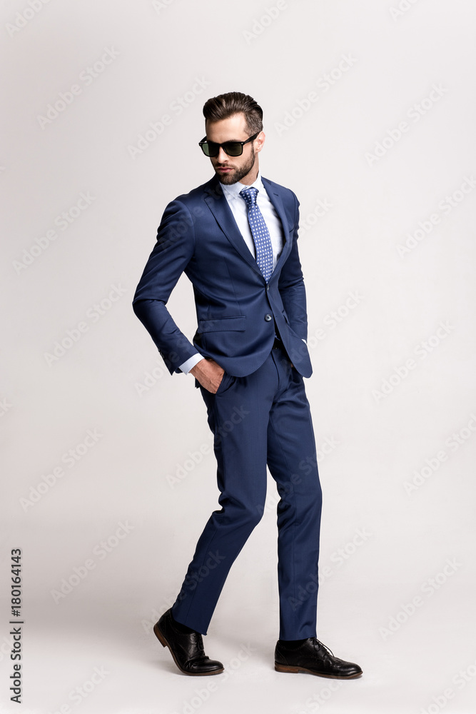 Perfect style on a go. Full length of handsome young man in suit and glasses looking away while standing against white background. Perfect style on a go. Full length of handsome young man in suit and glasses looking away while standing against white background.