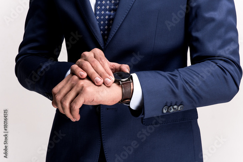 Time is business. Close-up part of man checking the time while standing against white background