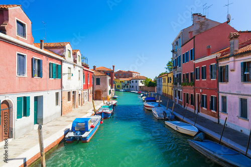 Venice landmark, Murano island canal, colorful houses and boats during summer day with blue sky in Italy. Venice lagoon.