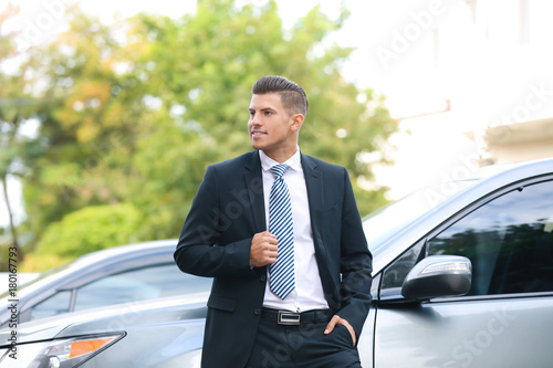 Attractive man in formal suit standing near car © Africa Studio