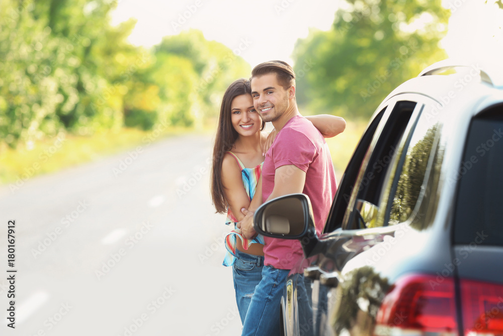 Fototapeta premium Beautiful young couple standing near car