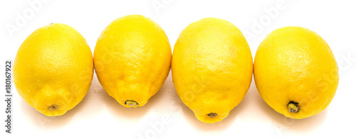 Group of four whole yellow lemons in row isolated on white background .