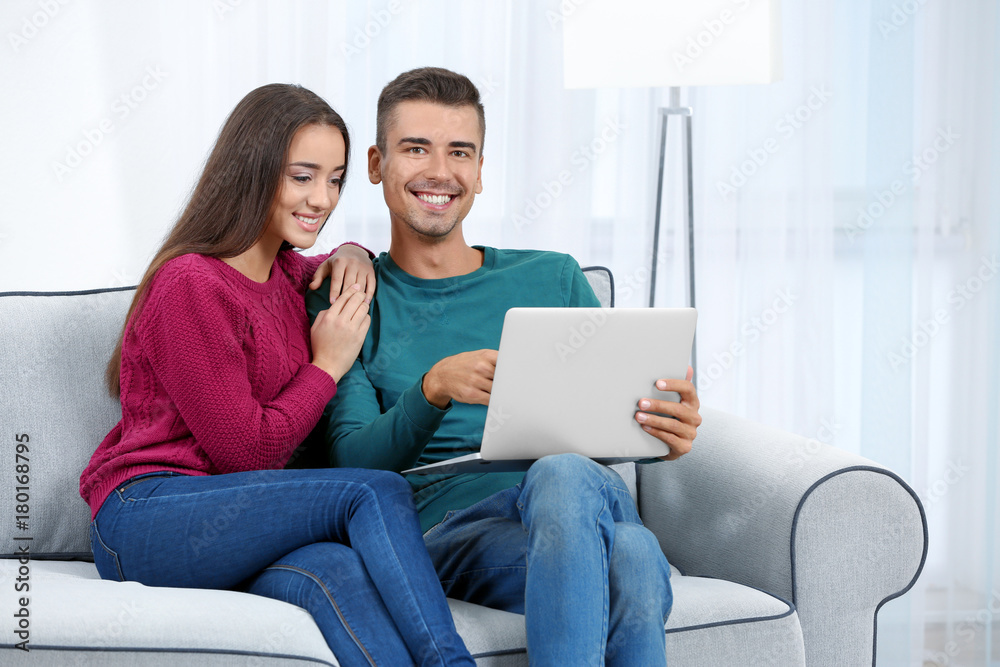Young couple with laptop on sofa at home