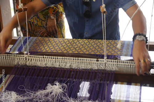 A man is using traditional weaving machines to weave songket. photo