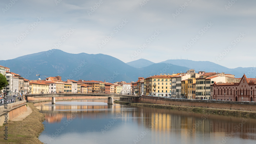 Ancient house with tower overlooking River Arno in Pisa, Tuscany, Italy with Apennine mountains in background
