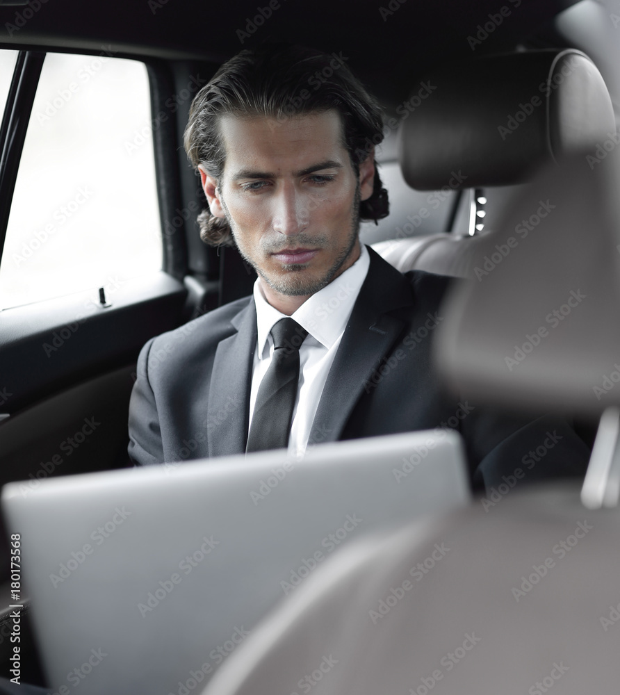 man working on laptop while sitting in the car