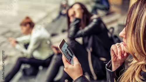Group of girls sitting on the city stairs with smartphone