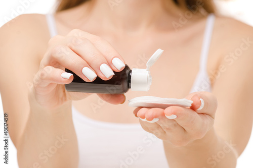 Beautiful woman sits lotion for a body of a cotton pad on a white background isolation