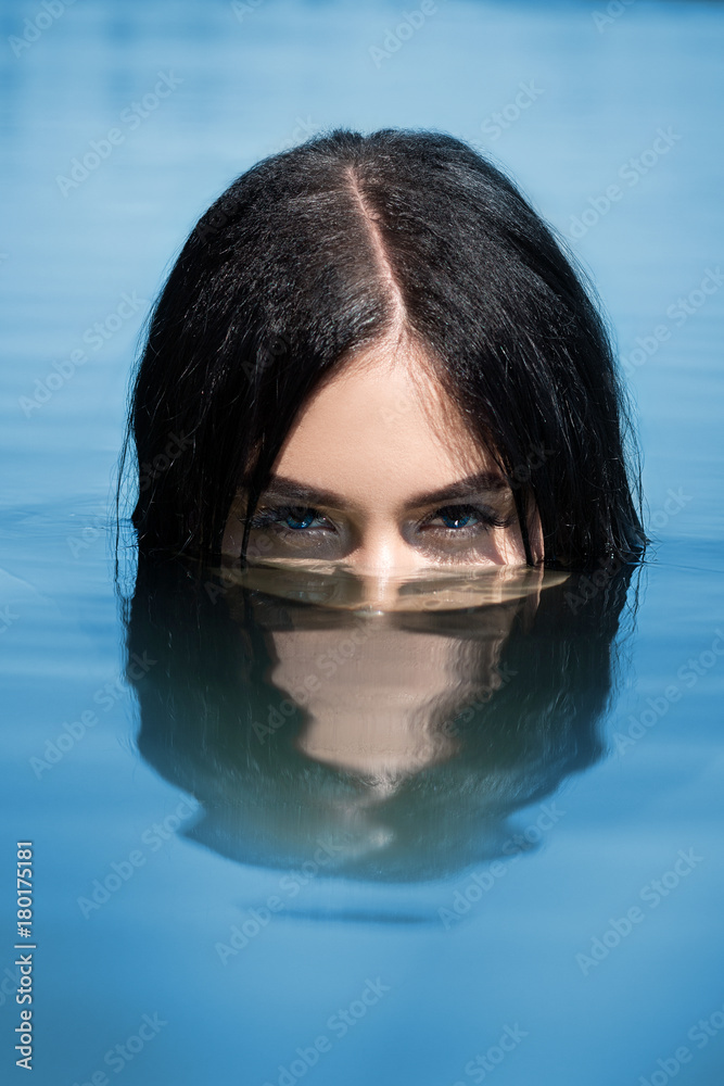 A sexy woman or girl, floating in the water, only the eyes are visible