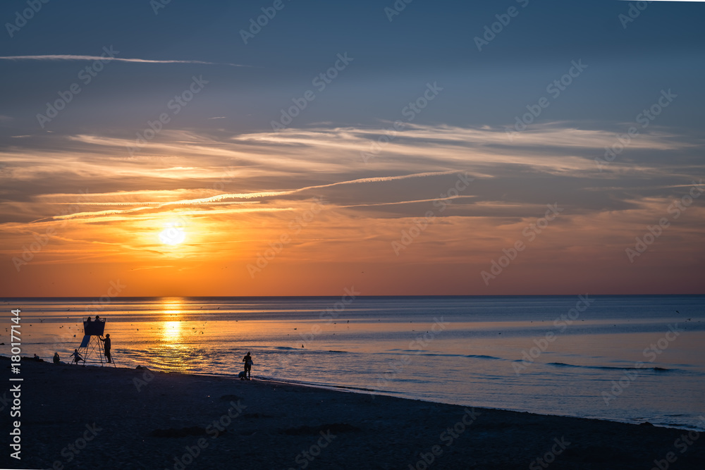People walking on the  beach in summer at sunset