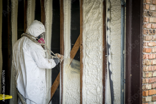 Worker spraying closed cell spray foam insulation on a home that was flooded by Hurricane Harvey