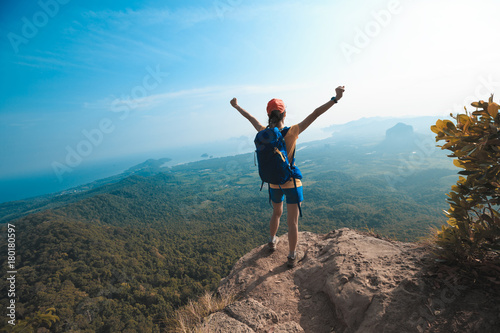 successful woman hiker enjoy the view on cliff edge top of mountain