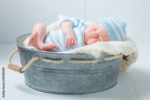 Sweet newborn sleeping in small bath with blanket