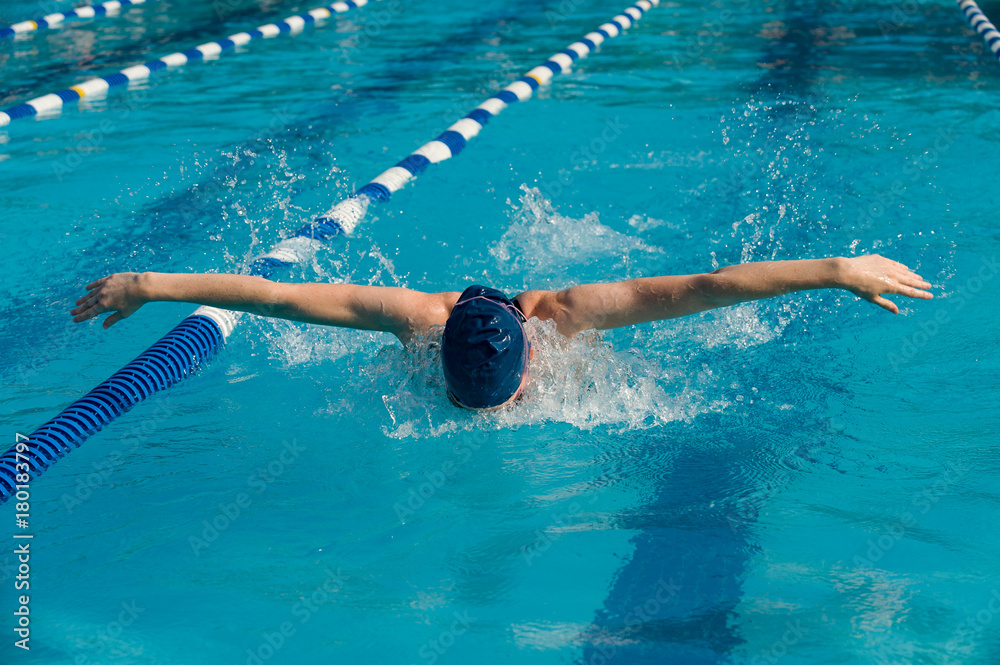 Teen female athlete competing in the butterfly stroke competition in a swim meet