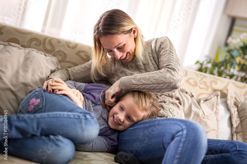Beautiful portrait of a happy woman tickling a daughter in bed